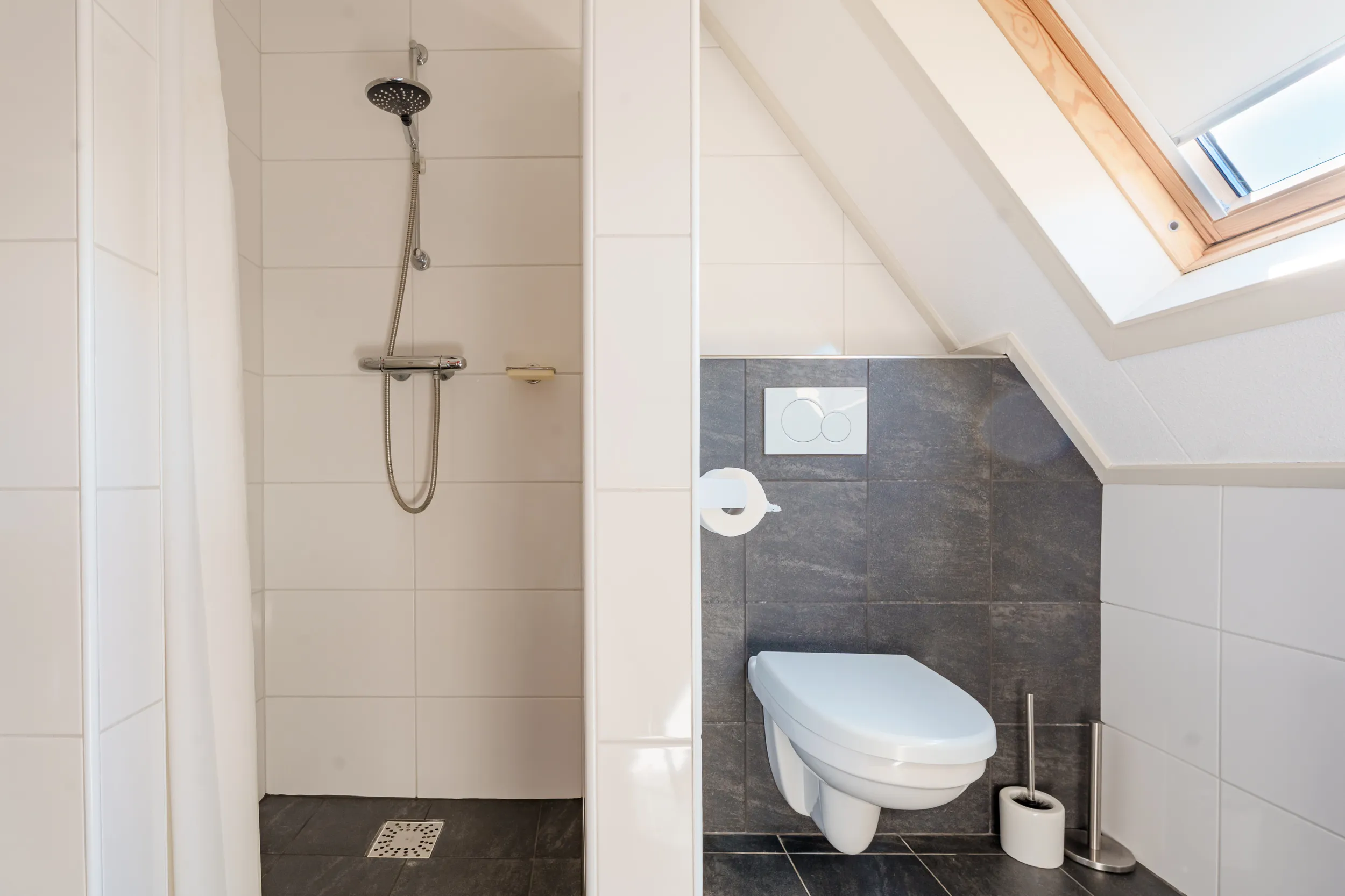 Badkamer met douche en toilet onder het schuine dak